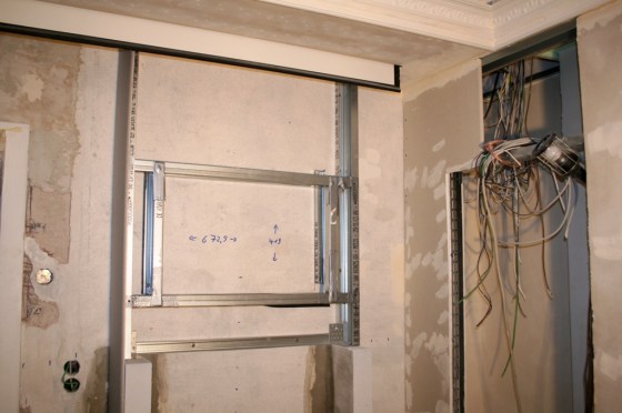 Über dem Ofen wird ein Fake-Kamin gebaut mit Aussparung für einen Touchscreen-Monitor. Dieser dient als Bedienzentrale für die Hausautomation und kann nebenbei auch TV darstellen. 